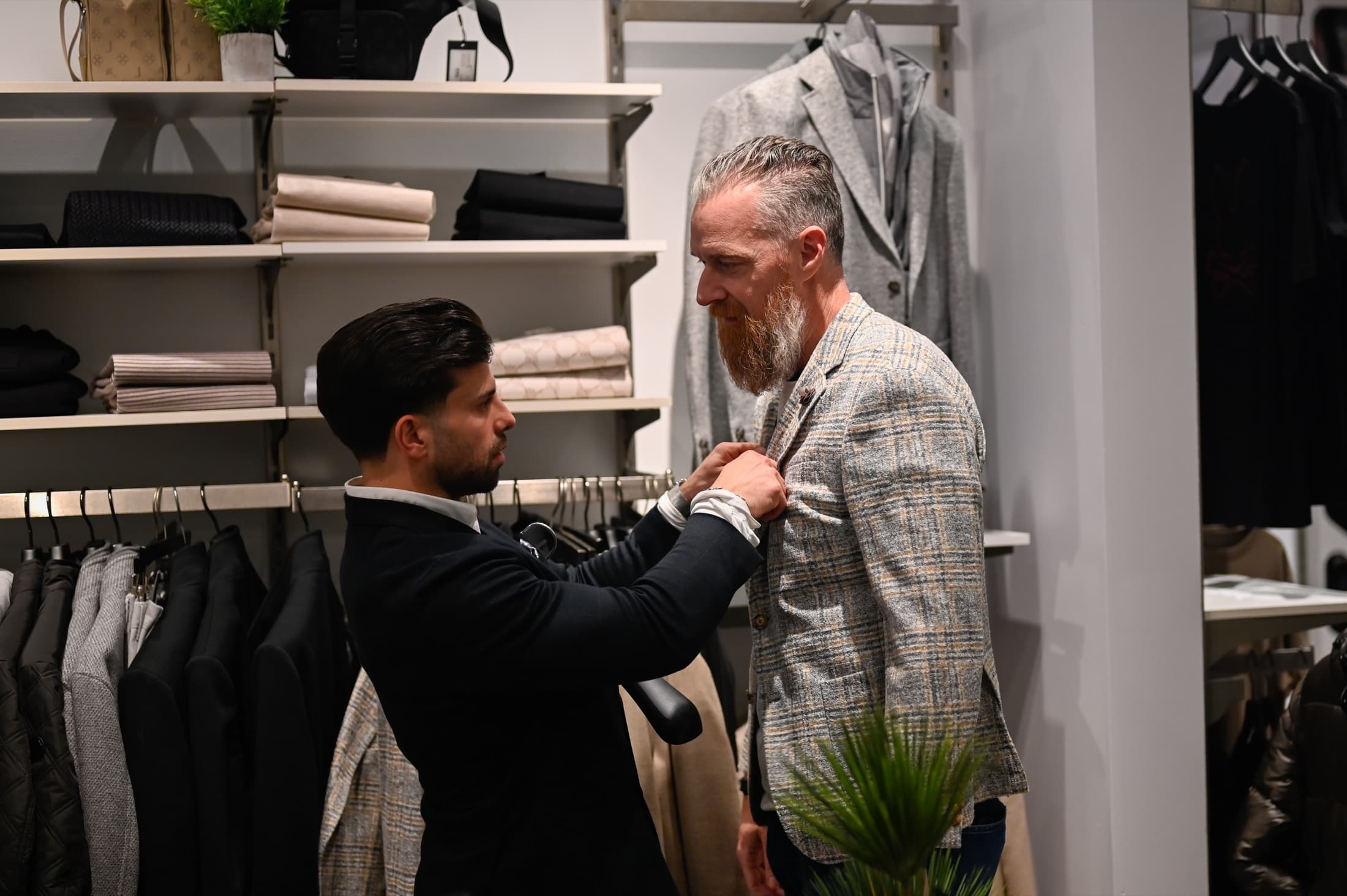 Un participant essaie un veston avec l'aide d'un styliste dans la boutique M2